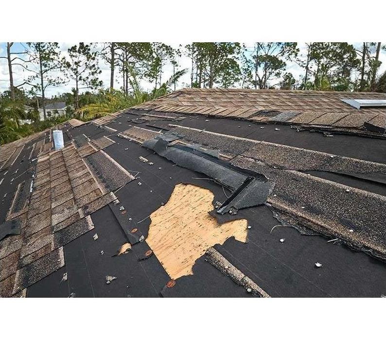 Residential roof with shingles broken and torn from wind and storm damage