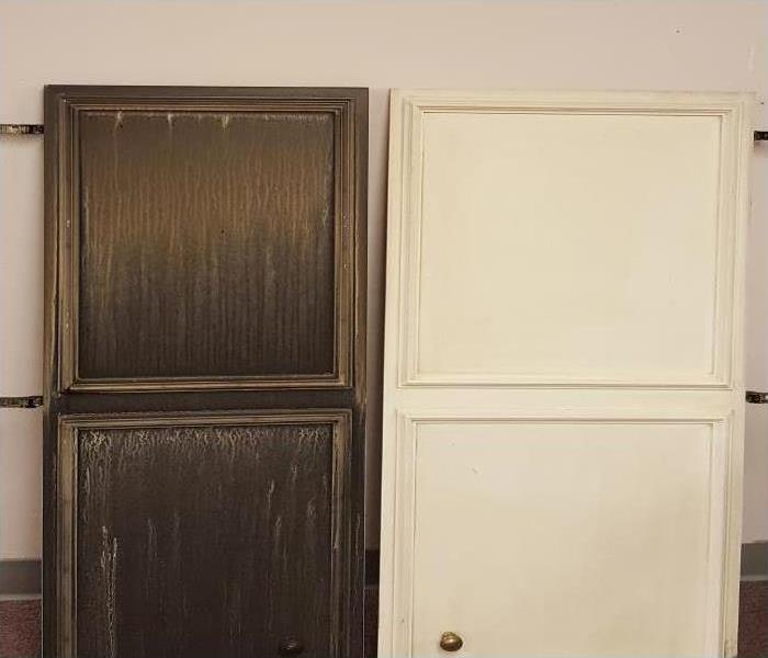 Soot and smoke damaged cabinet door next to a cleaned cabinet door